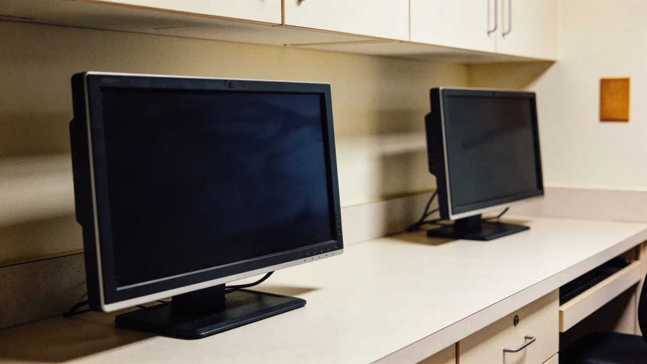 A logo-free clinic workstation with blank monitors before a digital health earnings report